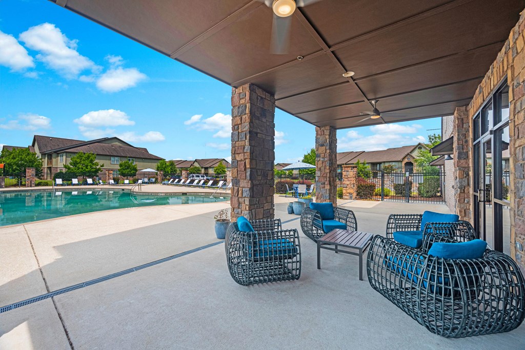 a covered patio with chairs next to a pool
