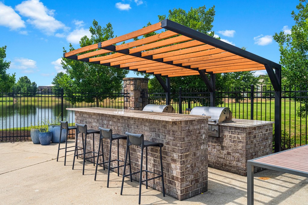 a patio with a bar with chairs and a grill
