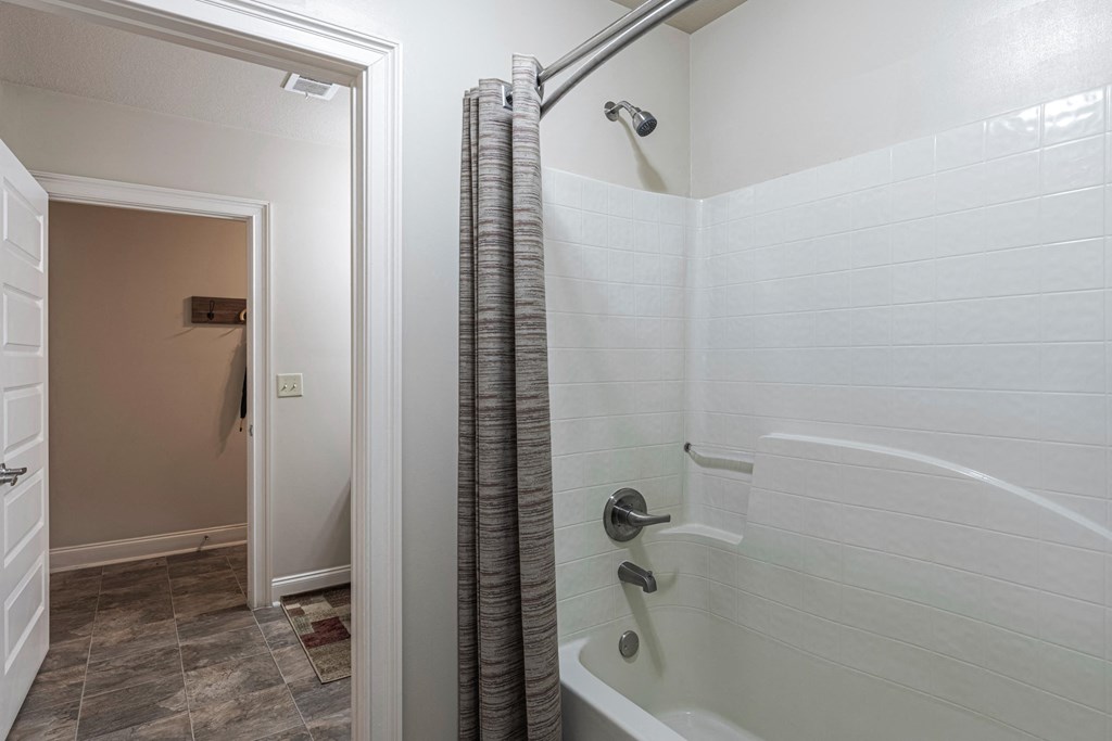 a bathroom with a shower and a tub and a door