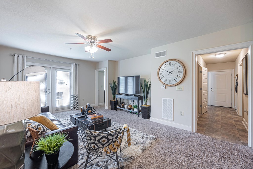 a living room with a ceiling fan and a large clock on the wall