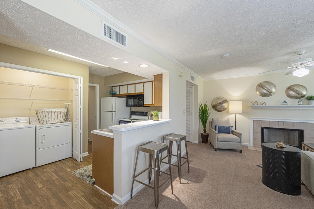 a living room with a kitchen and a bar with stools