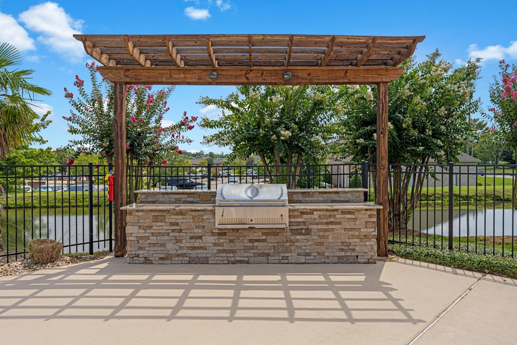 a patio with a stone fireplace and a wooden pergola