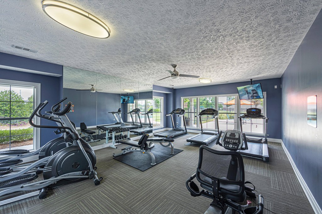 a gym with treadmills and other exercise equipment and windows