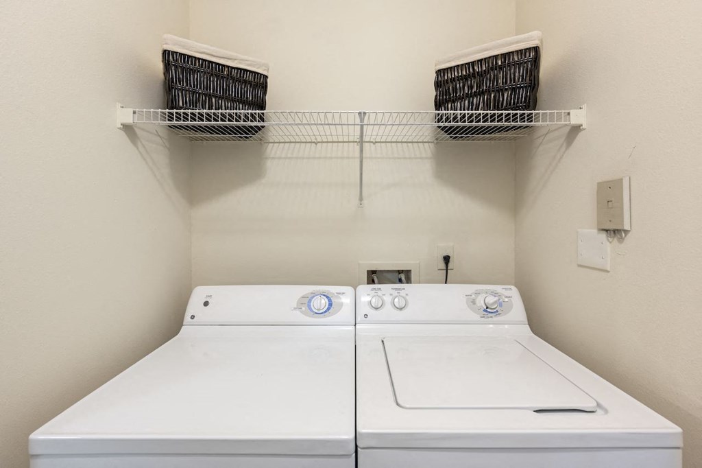 a washer and dryer in a laundry room with two baskets on the wall