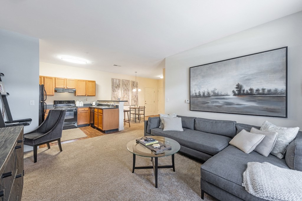a living room with a couch and a coffee table in front of a kitchen