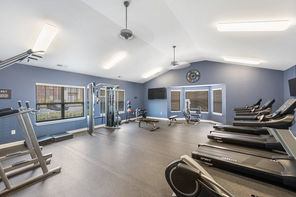 a gym with cardio machines and weights and a clock on the wall