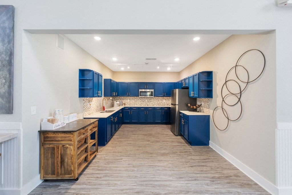 a kitchen with blue cabinets and white walls and wood floors