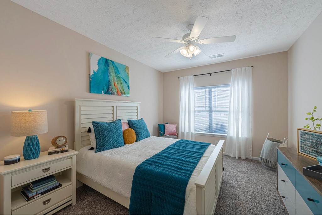 a bedroom with a white bed and a ceiling fan