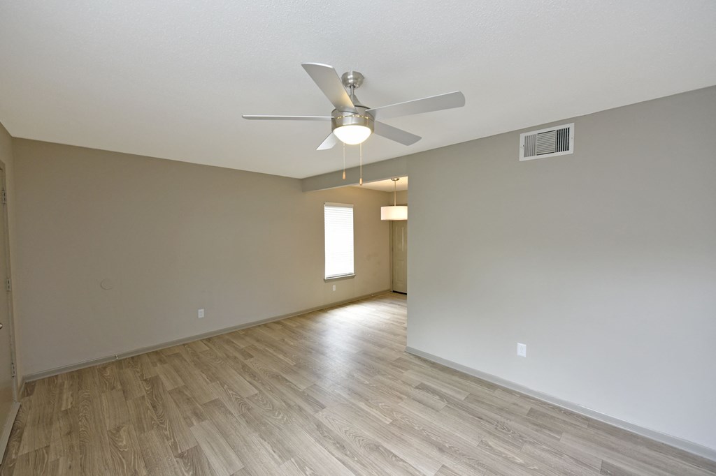 an empty living room with a ceiling fan