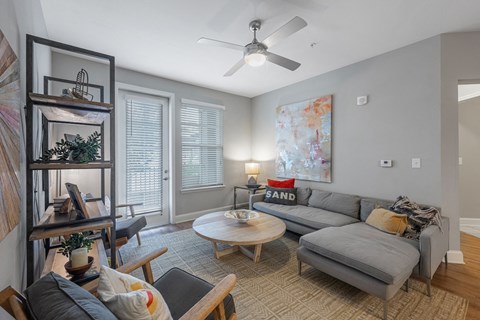 a living room with a gray couch and a ceiling fan
