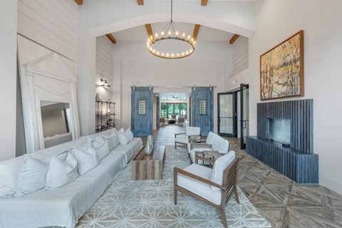 a long room with white couches and chairs and a chandelier