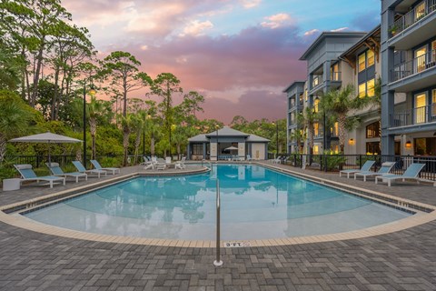 a swimming pool at dusk with an apartment building in the background