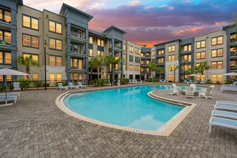 a swimming pool in front of an apartment building at sunset