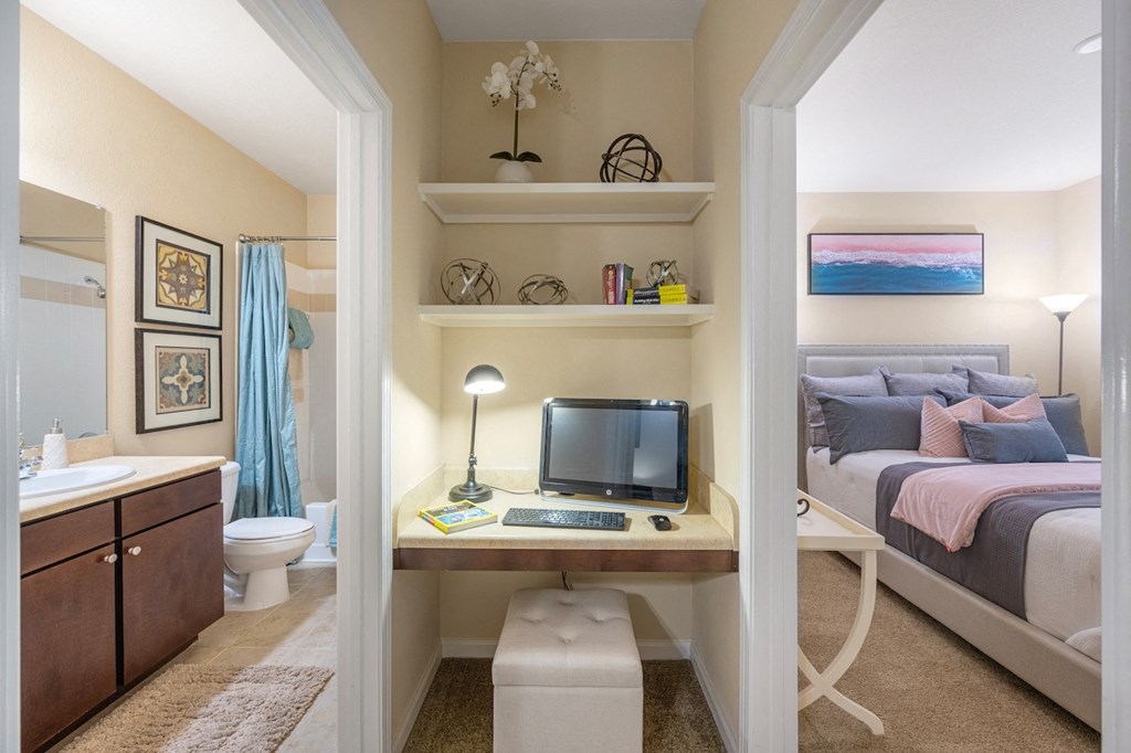 a bedroom with a bed and a desk with a computer and a bathroom
