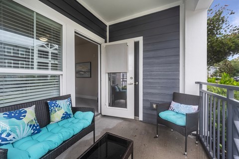 a covered porch with two chairs and a door