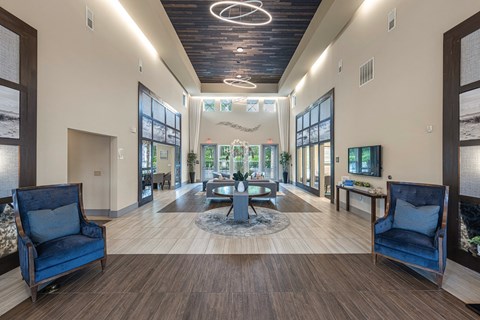a lobby with blue chairs and a table and a large window