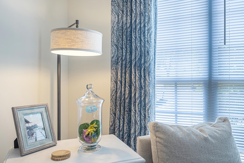 a corner of a room with a window and a table with a vase with