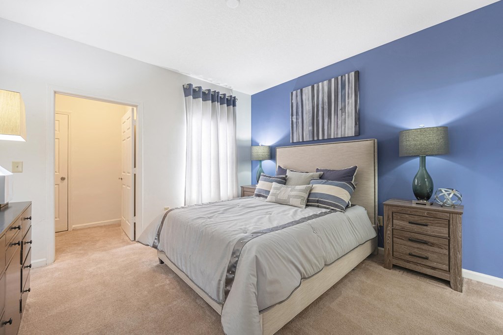 furnished bedroom with blue accent wall and a bed with white comforter