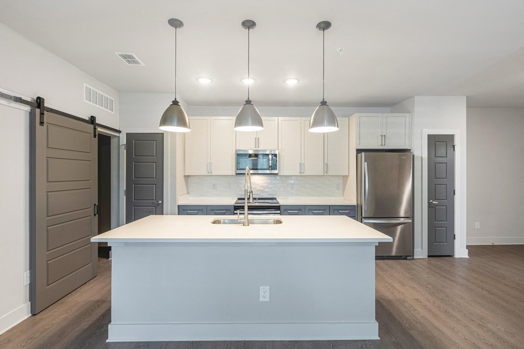 a white kitchen with a large island and stainless steel appliances