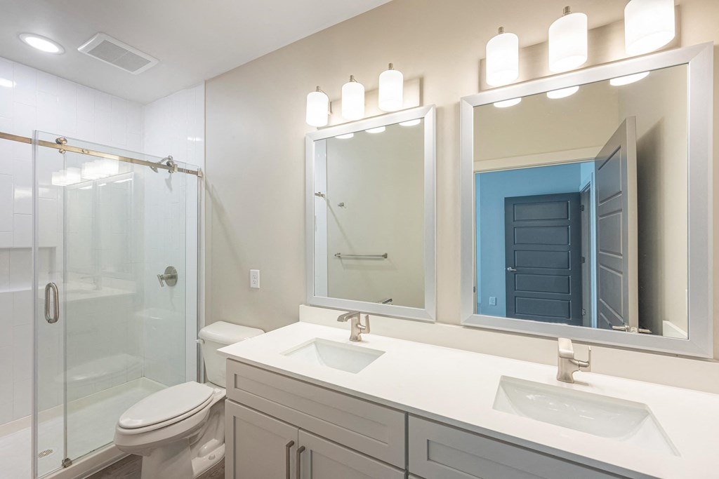 a white bathroom with two sinks and a shower
