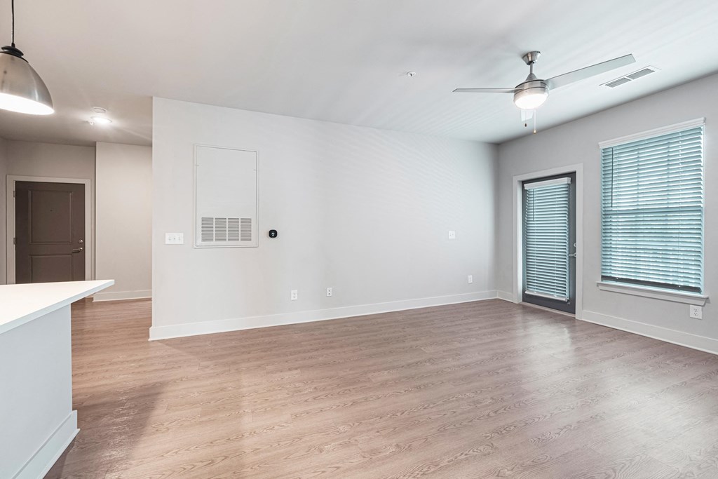 an empty living room with a ceiling fan and a window