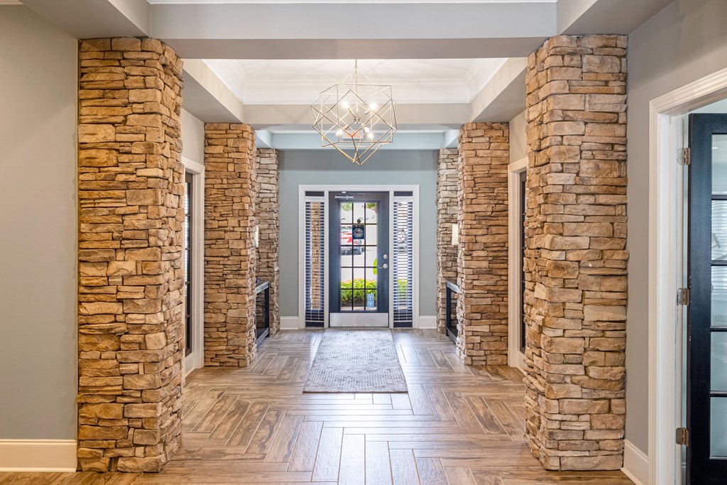 the lobby of a house with stone columns and a chandelier