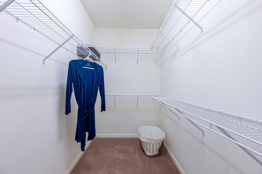 a walk in closet with a dress hangar and a trash can