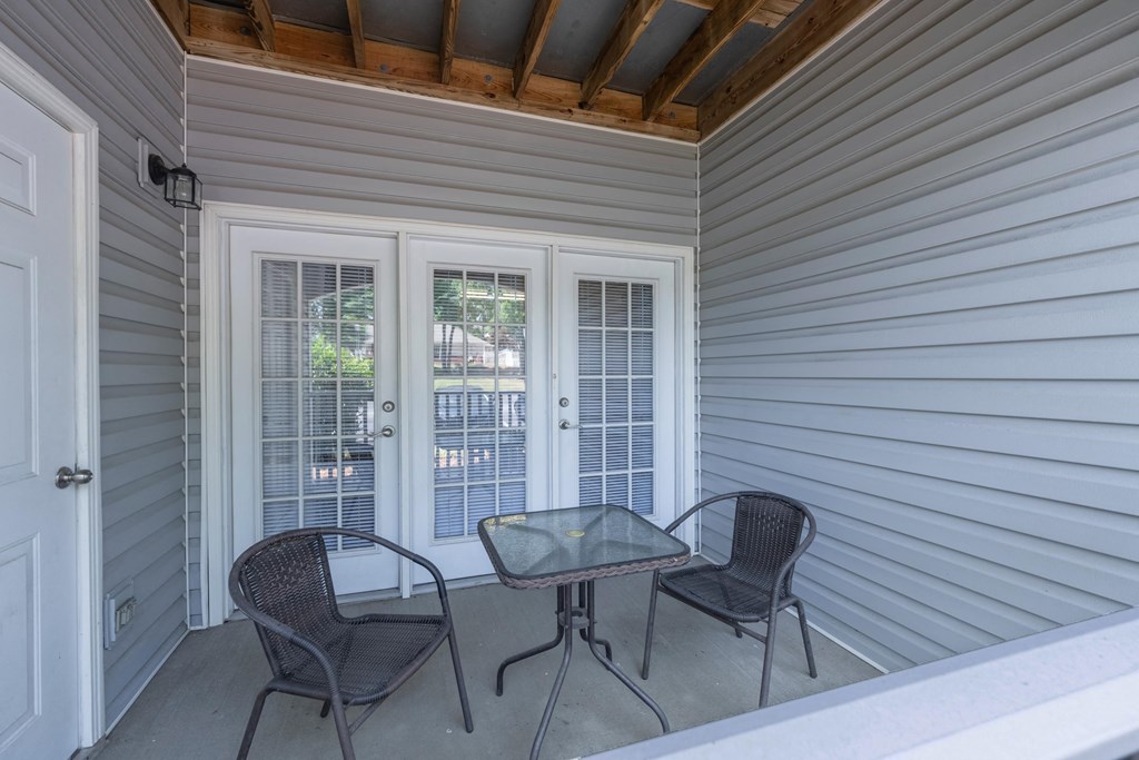 a covered porch with two chairs and a table
