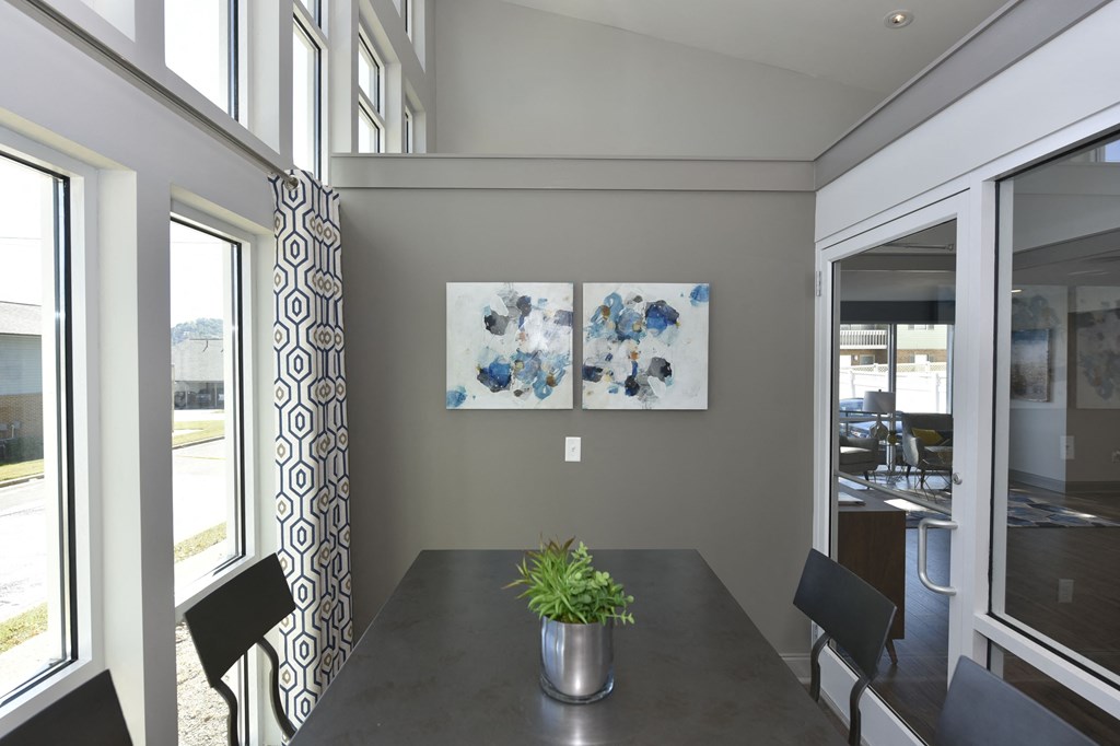 a dining area with a table and chairs and two paintings on the wall