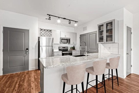 A kitchen with a white marble countertop and a refrigerator.