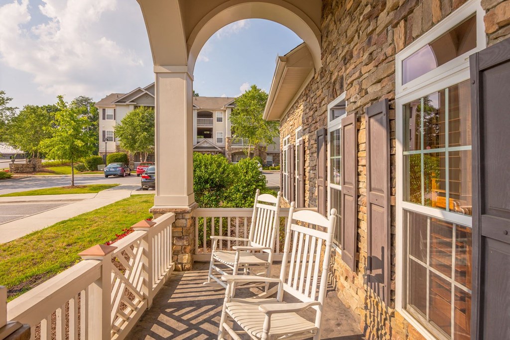 a porch with two rocking chairs and a balcony overlooking a street
