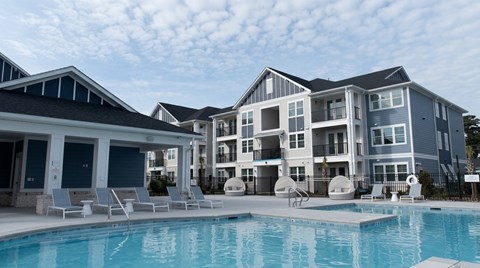 A large swimming pool in front of a multi-story residential building.