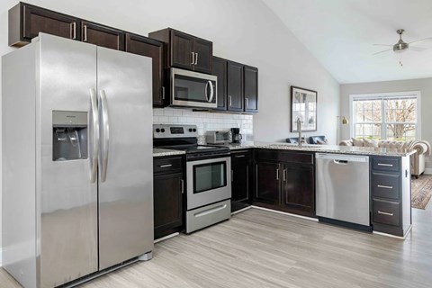 A modern kitchen with a stainless steel refrigerator and black cabinets.