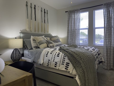 A bedroom with a bed, nightstand, and window.