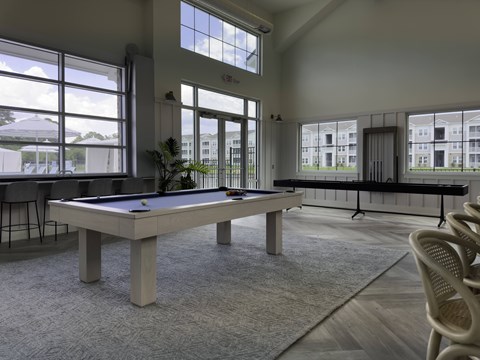 A billiard table in a room with a view of a building outside the window.
