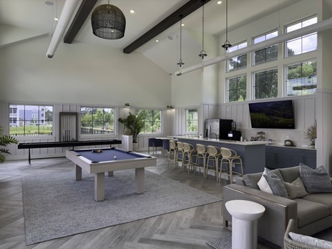 A billiard table is in the middle of a spacious room with a couch and a TV.