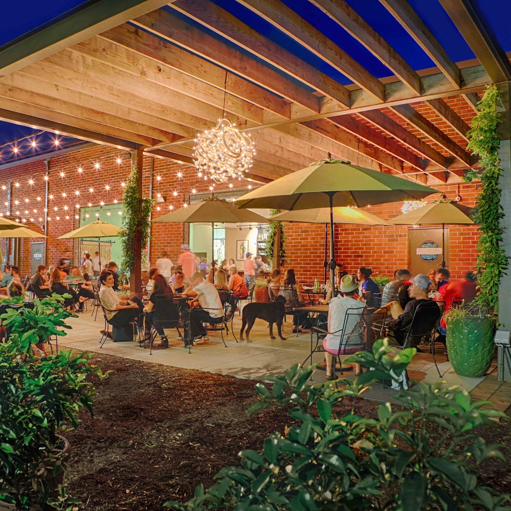 A group of people are sitting at tables under umbrellas in a courtyard.