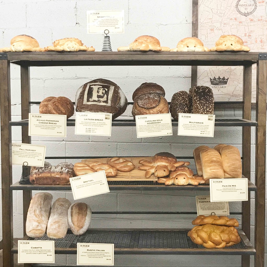 A display of various breads with labels on a shelf.