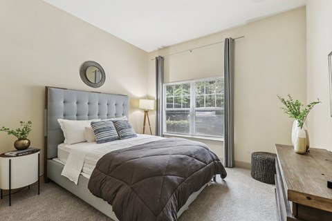 A bedroom with a large bed and a window with blinds.