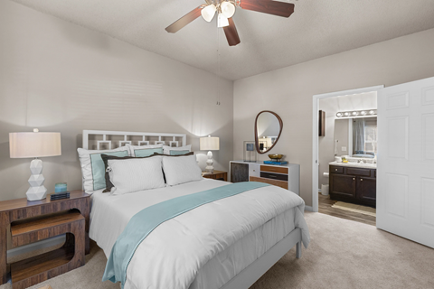 A bedroom with a large bed and a ceiling fan at Heights at New Garden apartments in Greensboro, NC.