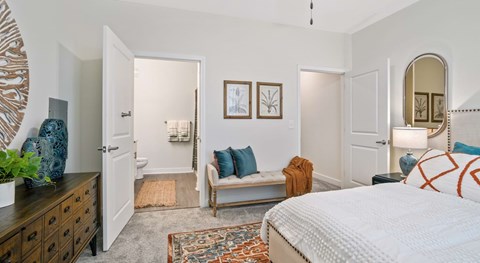 A bedroom with a bed, a couch, a dresser, and a mirror at the lorrel apartments in little river sc