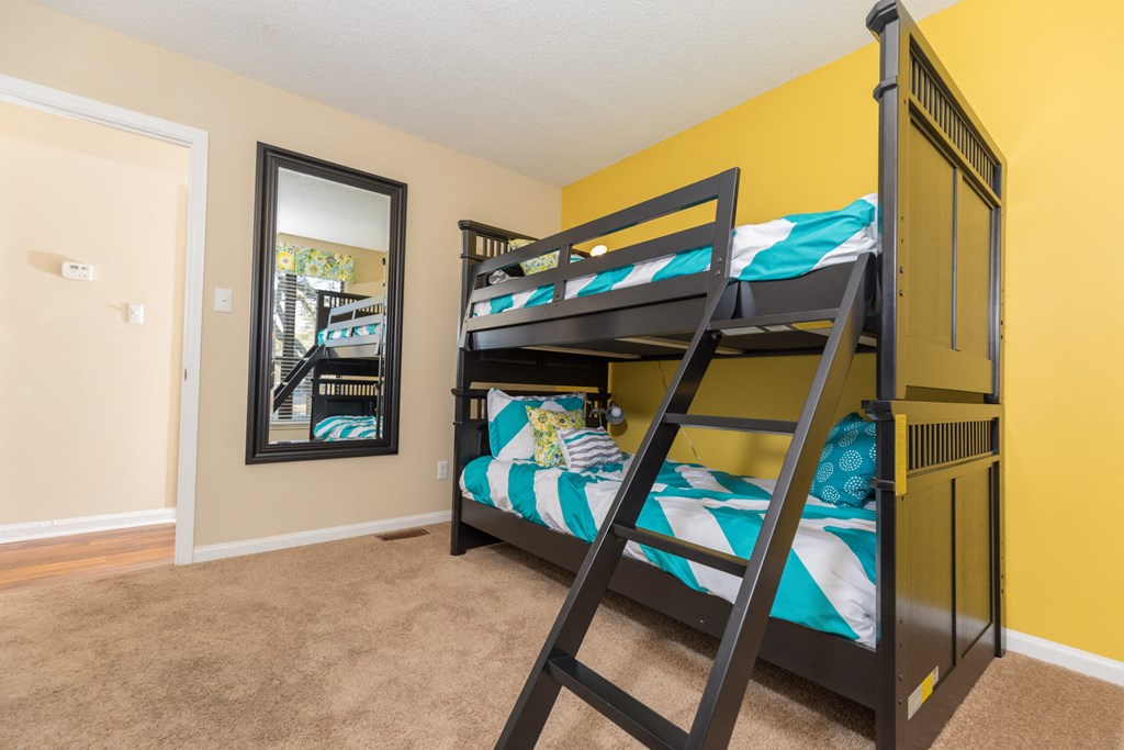 a bunk bed in a bedroom with yellow walls and a mirror