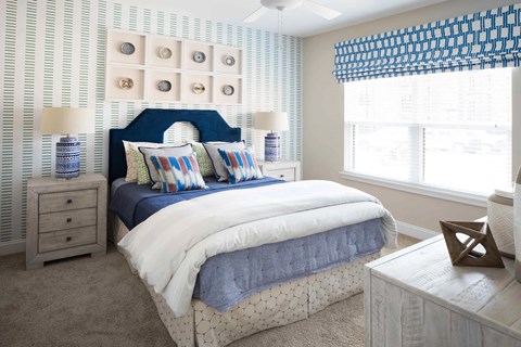 A bedroom with a bed, nightstands, and a window with a blue and white striped valance.