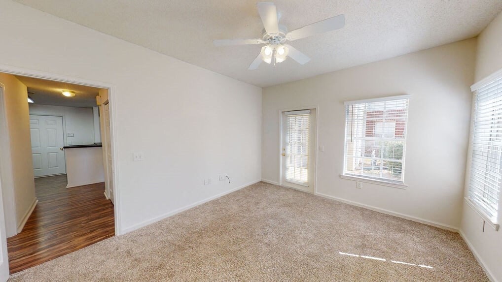 an empty living room with a ceiling fan and a window