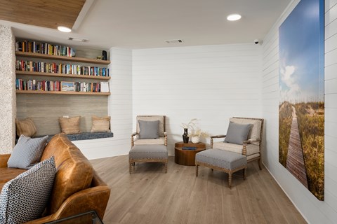 A living room with a couch, two chairs, and a bookshelf.