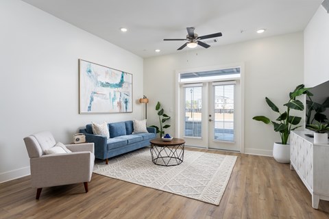 A living room with a blue couch, a chair, a coffee table, and a painting on the wall.