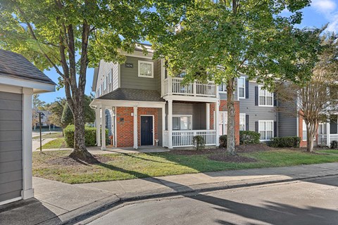 A two-story house with a red brick front door and a balcony.