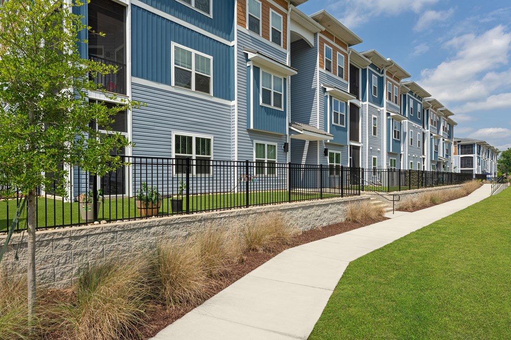 A long row of houses with a sidewalk in front.