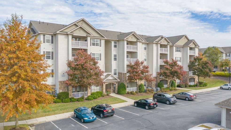 an apartment building with cars parked in a parking lot
