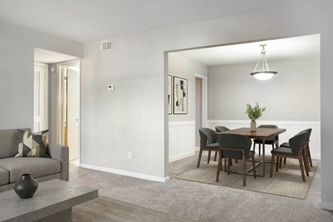 A modern living room with a grey couch and a grey dining table with six chairs.